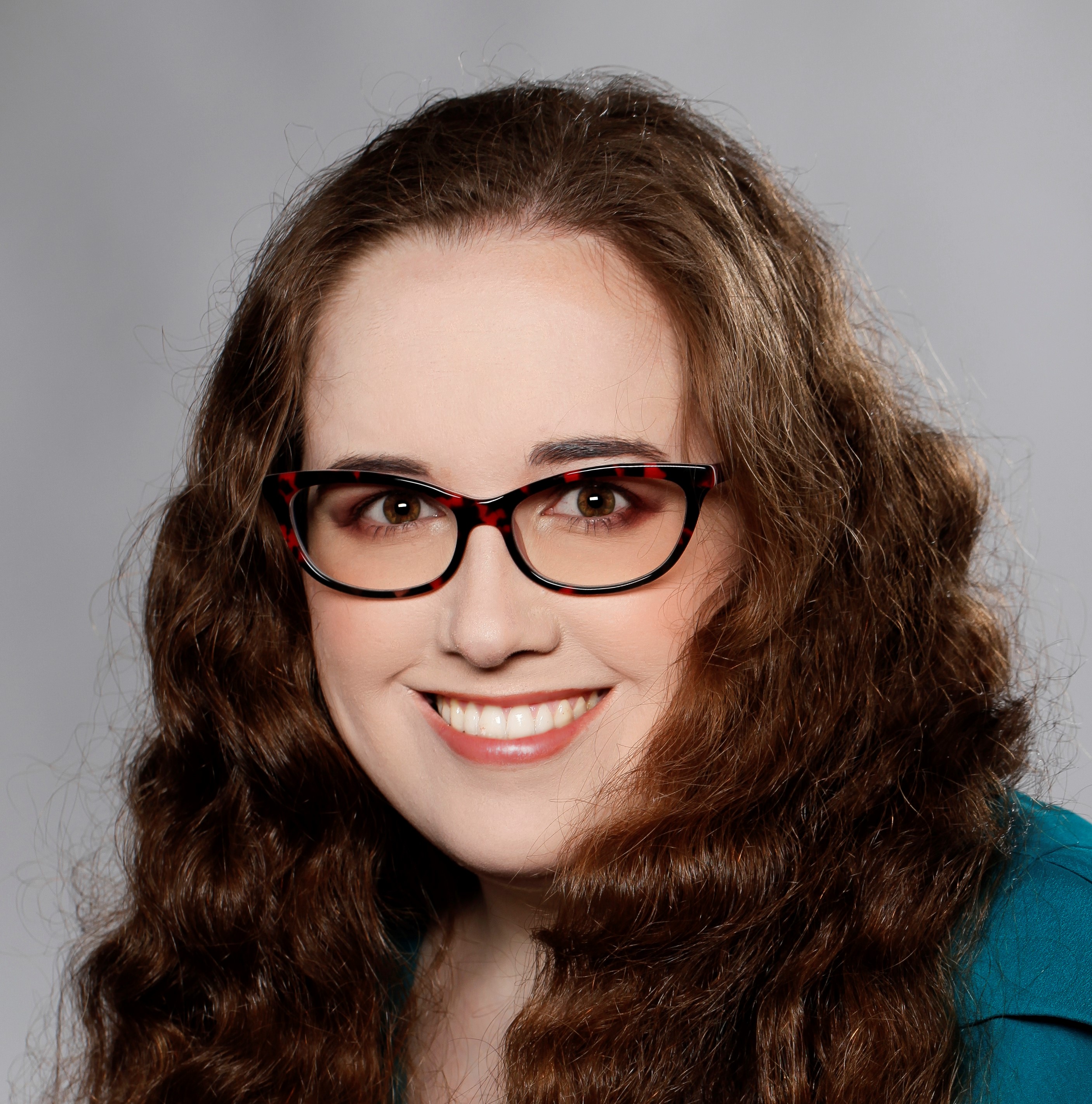 Miranda Lane. Profession headshot. Woman with red hair, red glasses, and hazel eyes smiling.